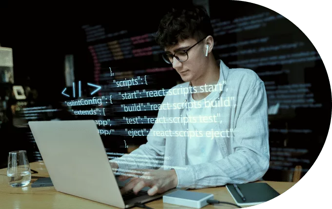 A focused individual programming on a laptop with code projected in the background.